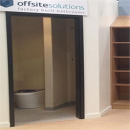 Doorway to Offsite Solutions Bathroom Pod Exhibit. Company Banner Above Doorway