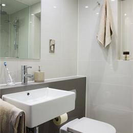 Corner View of Care Home Bathroom Pod, White Walls, Granite Effect Feature Wall Behind Toilet
