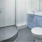 zoomed in version of military bathroom pod there's a dark grey corner round shower and white walls